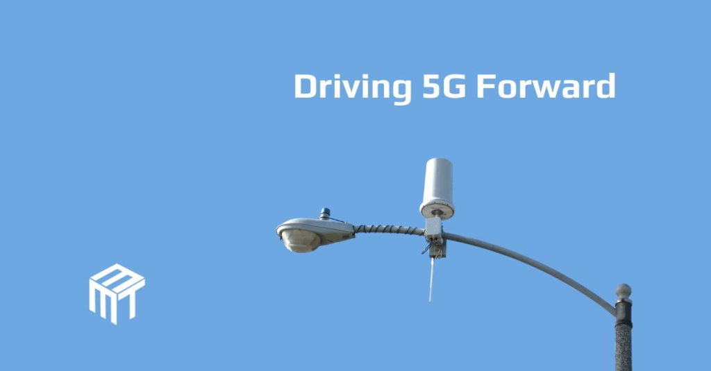 Under the title Driving 5G Forward is a street light with an antenna mounted on top of the arm between the post and light